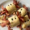 Snack di würstel per Halloween avvolti in pasta sfoglia, per feste e aperitivi. I würstel sono tagliati e incisi per creare divertenti tentacoli che si arricciano durante la cottura, mentre la pasta sfoglia dorata li avvolge al centro. Decorati con pezzetti di olive nere, questi finger food assumono un aspetto giocoso, ideali per buffet o eventi informali. Scopri come preparare questo stuzzichino sfizioso e originale in pochi semplici passi