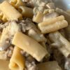 Piatto di pasta cremosa con salsiccia e funghi champignon