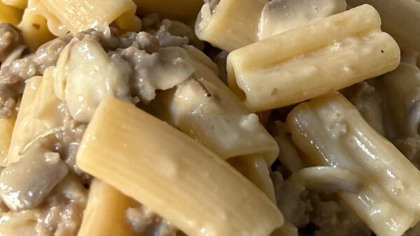 Piatto di pasta cremosa con salsiccia e funghi champignon