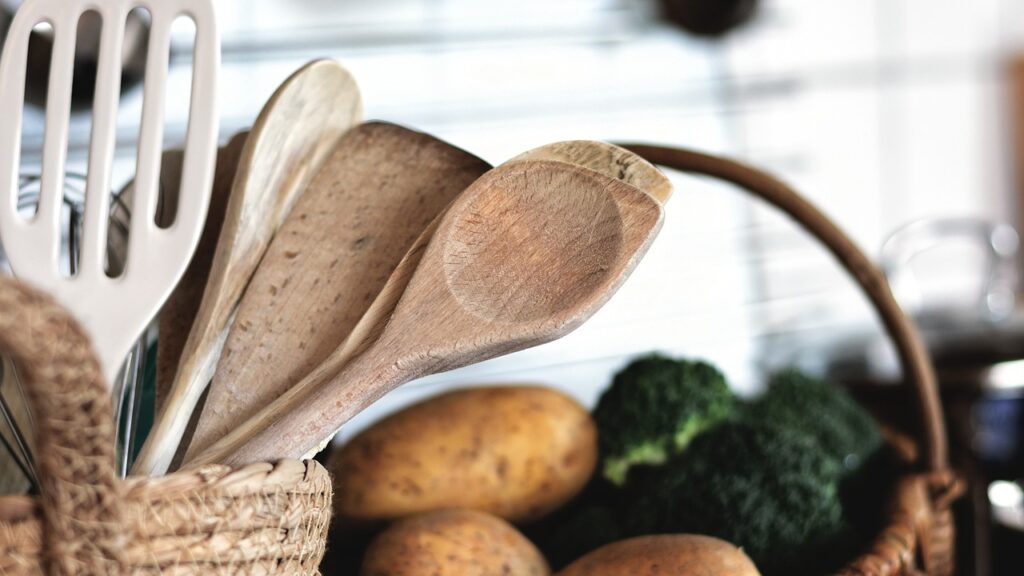 Sostituire utensili da cucina. Immagine di mestoli in una cucina con delle verdure sullo sfondo.