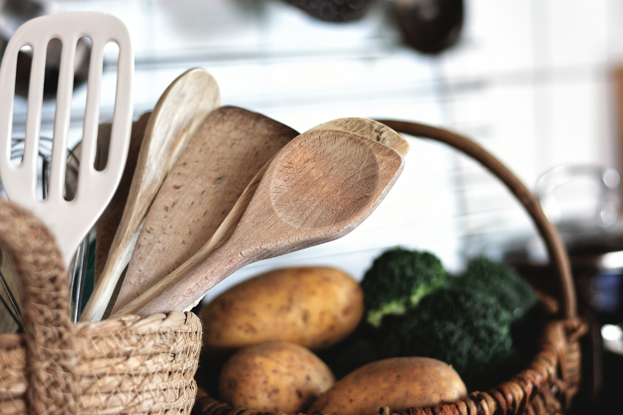 Sostituire utensili da cucina. Immagine di mestoli in una cucina con delle verdure sullo sfondo.