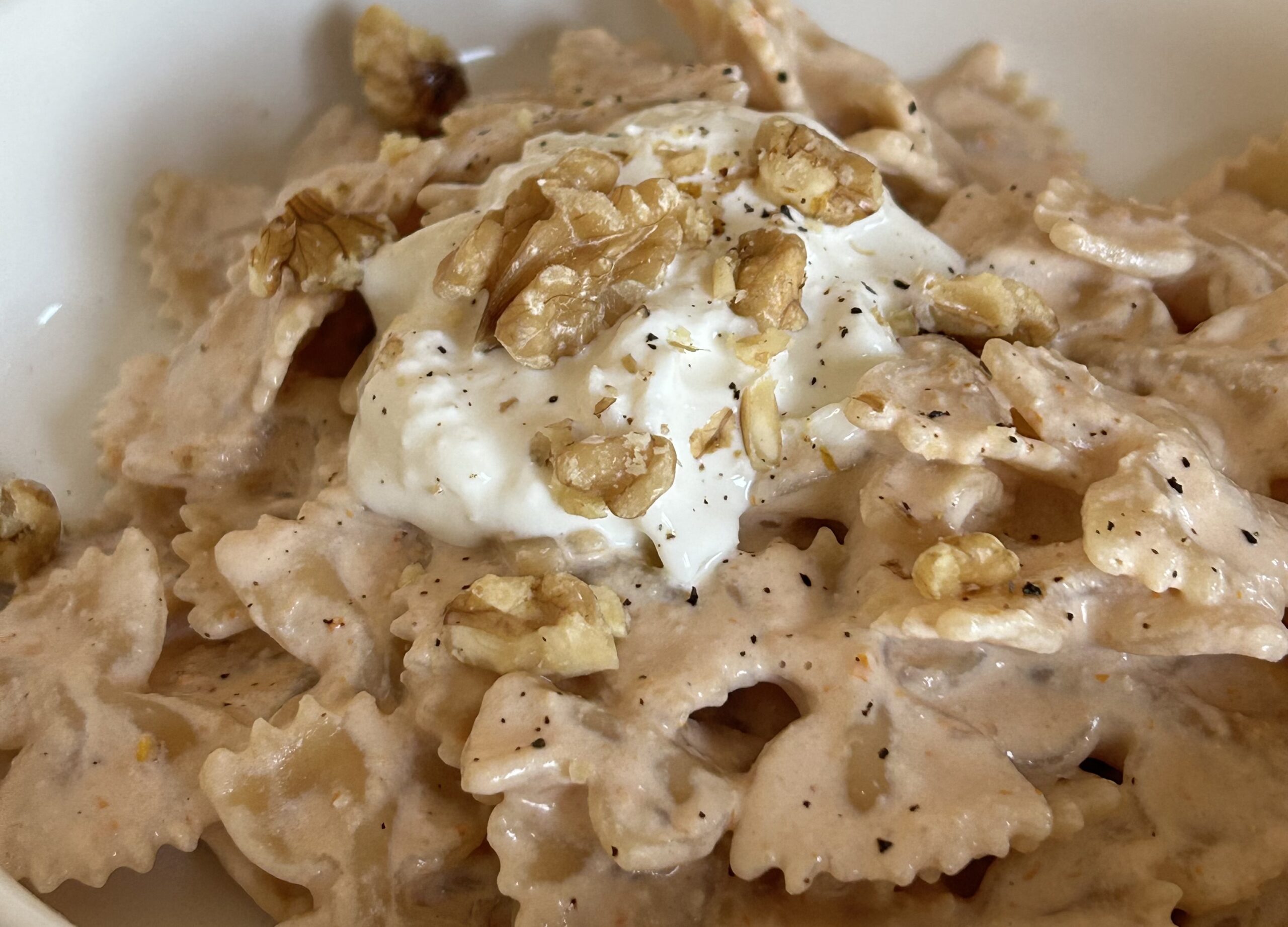 Pasta formato farfalle con crema di pomodorini secchi, stracciatella di burrata e noci. Pasta cremosta guarnita con stracciatella di burrata e noci a pezzetti.